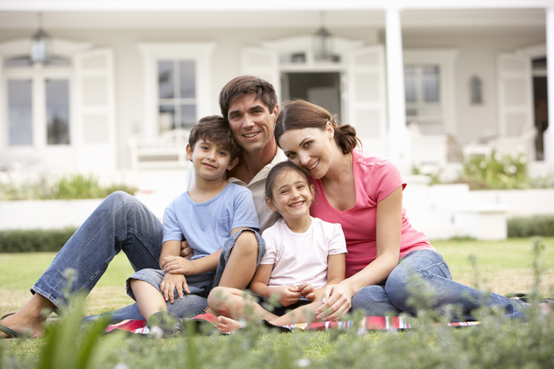 Family-Sitting-Outside-House-On-Lawn